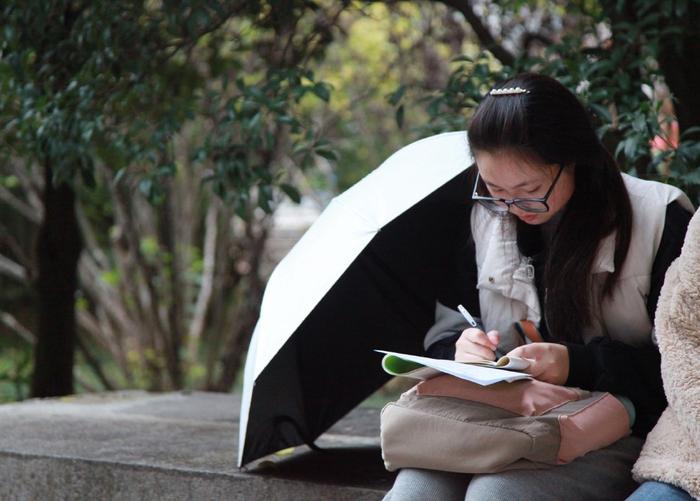 2023年11月26日,江苏省南京市,国考公共科目笔试考点外,考生在等候进场时复习。ic 图